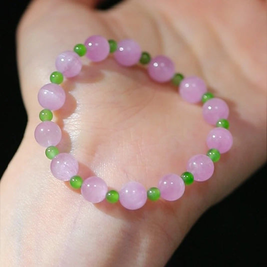 Womans hand wearing a pink crystal and green jade beaded bracelet in modern chinese style