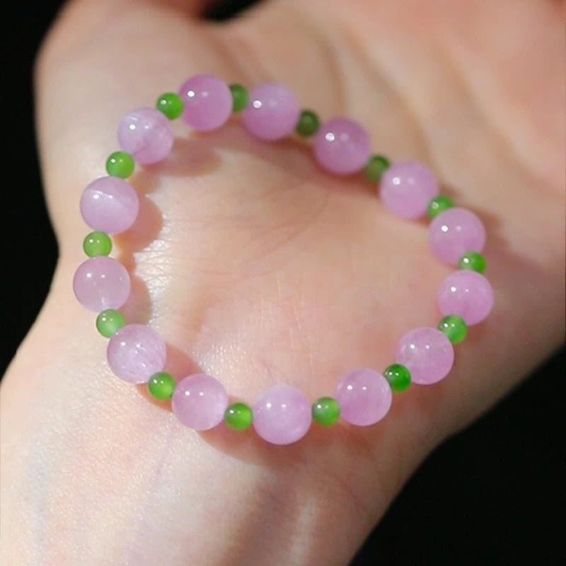 Womans hand wearing a pink crystal and green jade beaded bracelet in modern chinese style