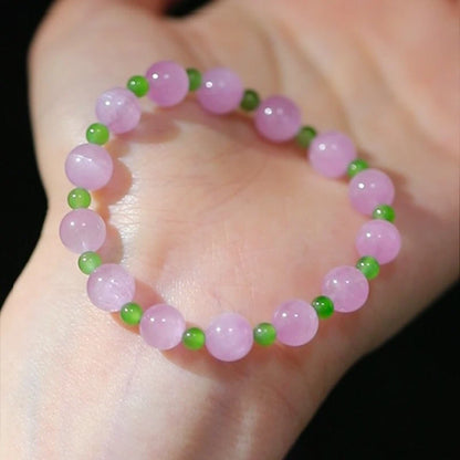 Womans hand wearing a pink crystal and green jade beaded bracelet in modern chinese style