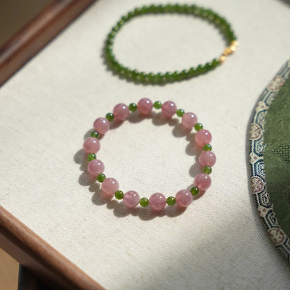 Womans hand wearing a pink crystal and green jade beaded bracelet in modern chinese style