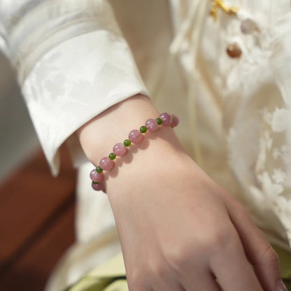 Womans hand wearing a pink crystal and green jade beaded bracelet in modern chinese style