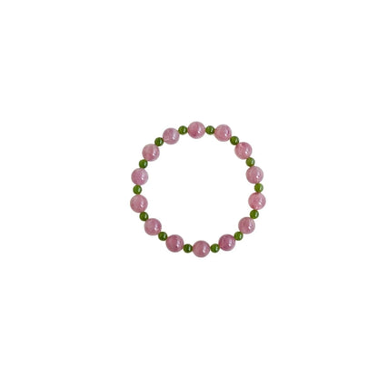 Womans hand wearing a pink crystal and green jade beaded bracelet in modern chinese style
