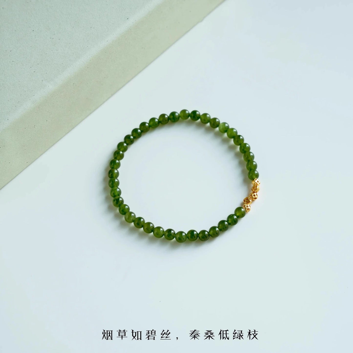 Womans hand wearing a pink crystal and green jade beaded bracelet in modern chinese style