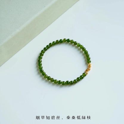 Womans hand wearing a pink crystal and green jade beaded bracelet in modern chinese style