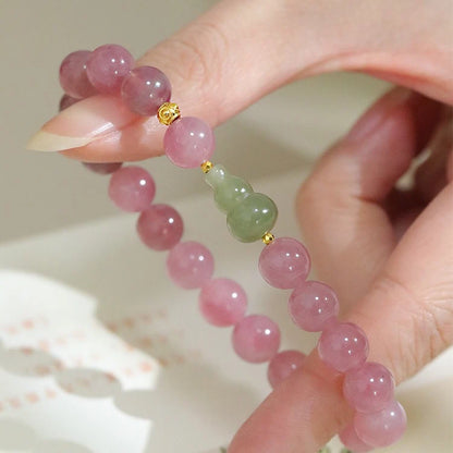 Womans hand wearing a pink crystal and green jade beaded bracelet in modern chinese style